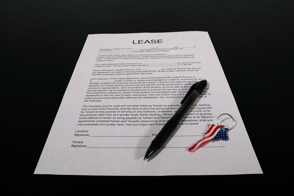 A close-up of a printed lease agreement form placed on a black surface, featuring clearly visible text with sections for landlord and tenant signatures. Resting on the document is a black ballpoint pe